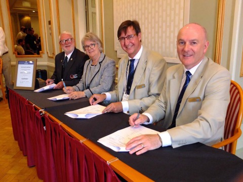 Signing the Master Contract: left to right: Brian Allen, Chairman Guernsey IGA; Dame Mary Perkins, Chair, 2021 Organising Committee; Jorgen Pettersson, Chairman IIGA; James Johnston Vice-Chairman IIGA. Photo by Bob Kerr